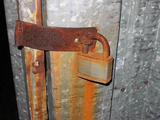 Porta em chapa de aço com proteção e cadeado enfferjudado pela ação do tempo. Foto Flickr @bobu Porta em chapa de aço com proteção e cadeado enfferjudado pela ação do tempo